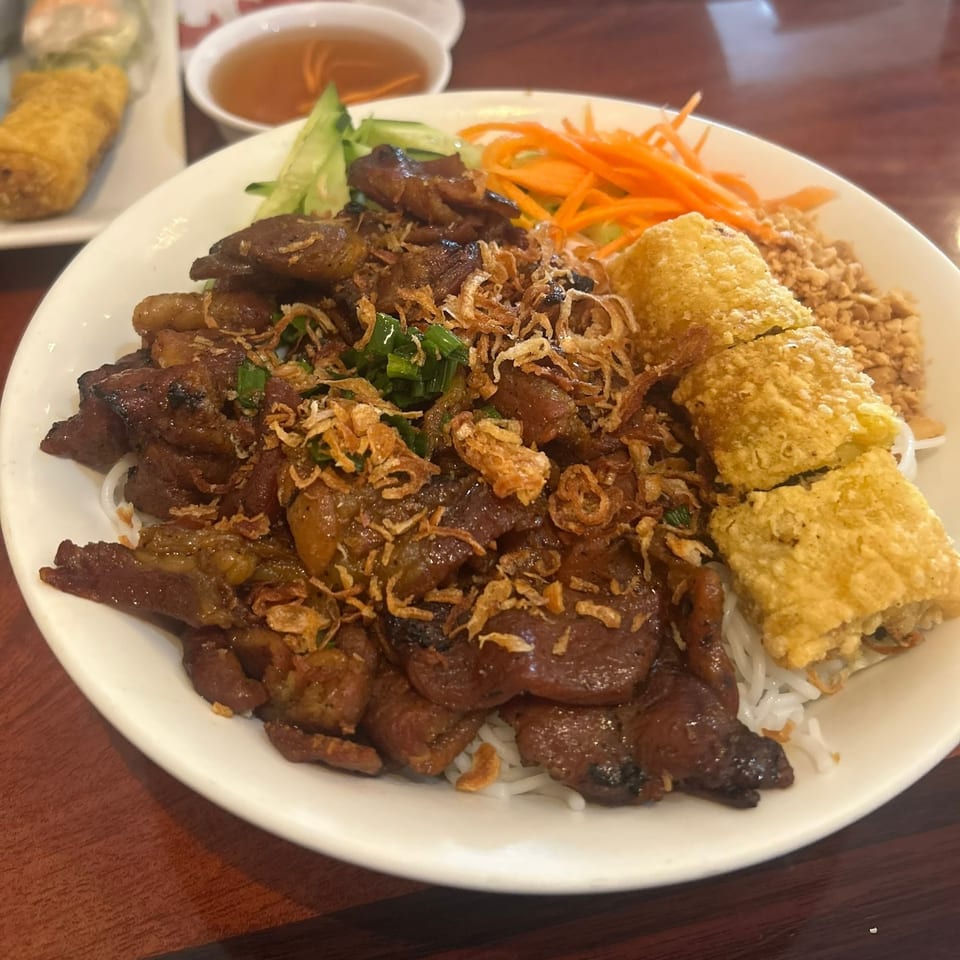 Vietnamese vermicelli bowl with grilled pork, fried spring rolls, shredded carrots, cucumber, and fried onions.